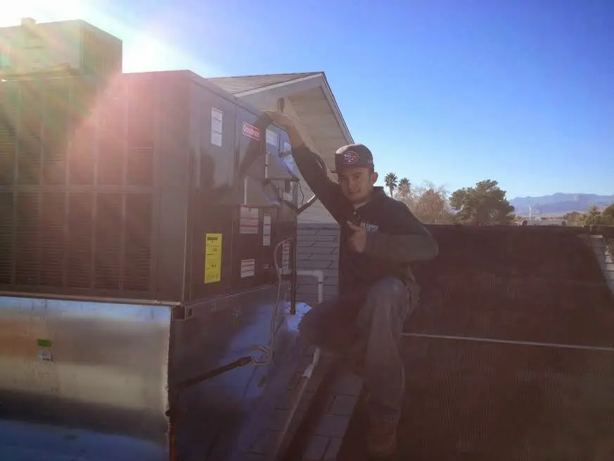 HVAC technician performing AC Tune-Up on a rooftop unit in Biloxi